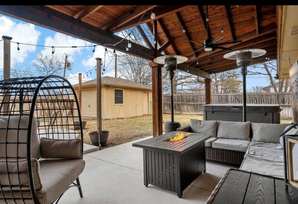 1603 Vicksburg Drive, Sachse, TX 75048 View of patio featuring ceiling fan, a fenced backyard, an outdoor structure, and an outdoor living space with a fire pit