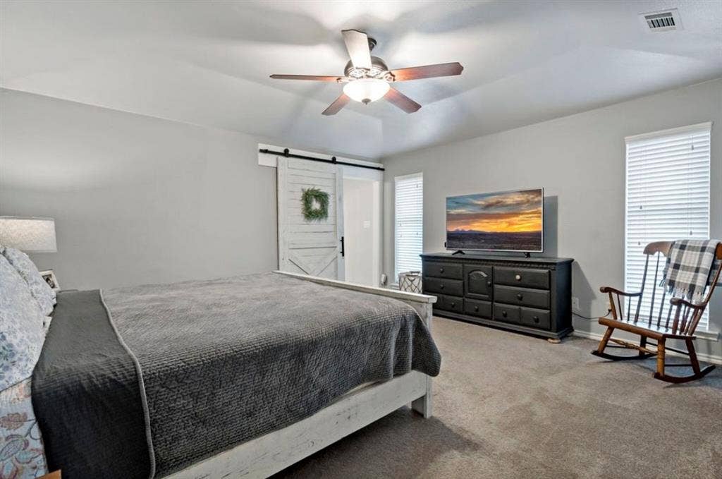 1603 Vicksburg Drive, Sachse, TX 75048 Carpeted bedroom featuring a ceiling fan, visible vents, baseboards, and a barn door