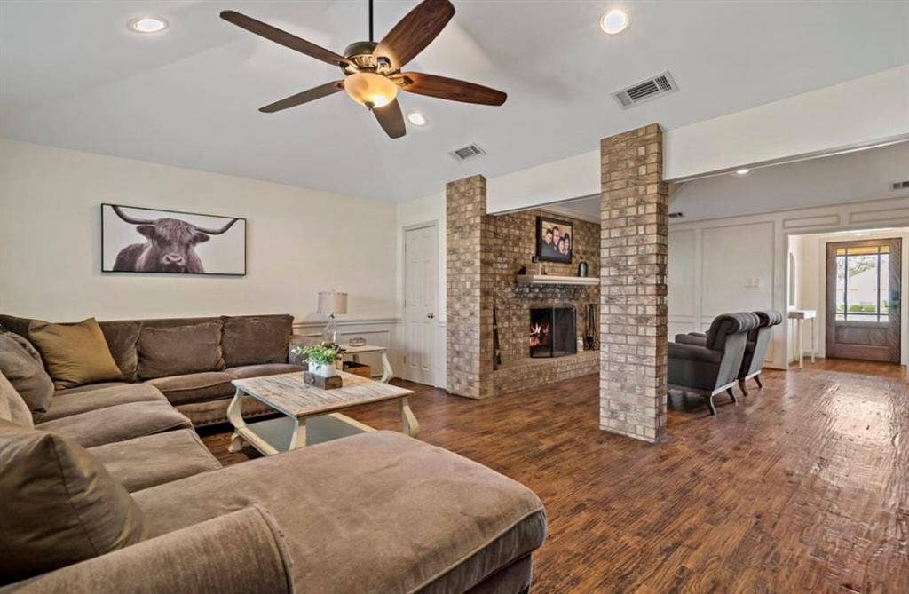 1603 Vicksburg Drive, Sachse, TX 75048 Living area featuring ornate columns, dark wood-style floors, visible vents, and a decorative wall