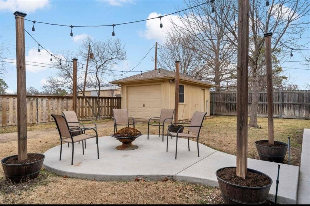 1603 Vicksburg Drive, Sachse, TX 75048 View of patio featuring a fenced backyard, an outdoor structure, a fire pit, and a detached garage