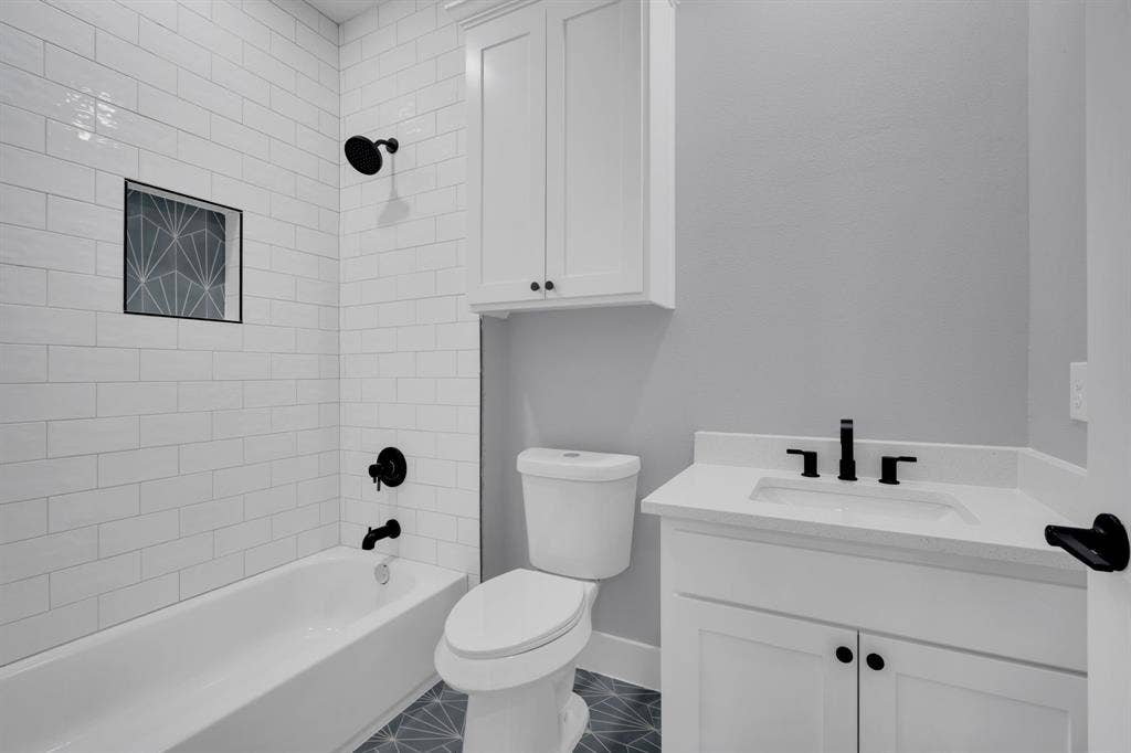 1995 Lakeview Drive, Kemp, TX 75143 White subway tile shower surround with black fixtures, white vanity with integrated sink, patterned floor tile, and built-in storage cabinetry