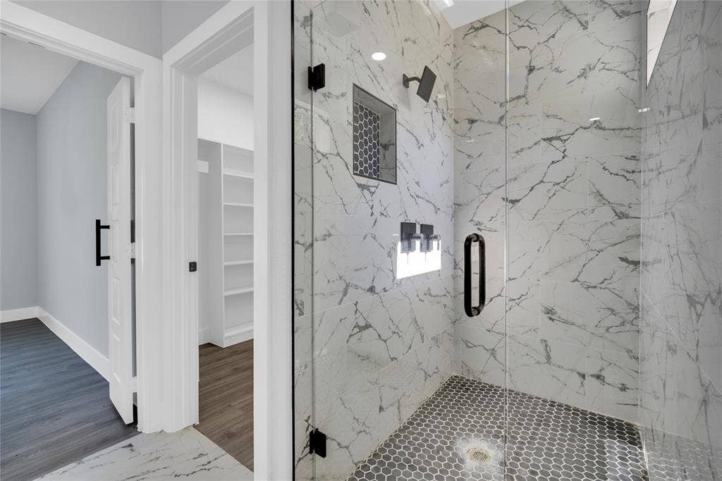 1995 Lakeview Drive, Kemp, TX 75143 Shower featuring full-height marble-look tile, frameless glass enclosure, black hex-tile flooring, and a recessed niche