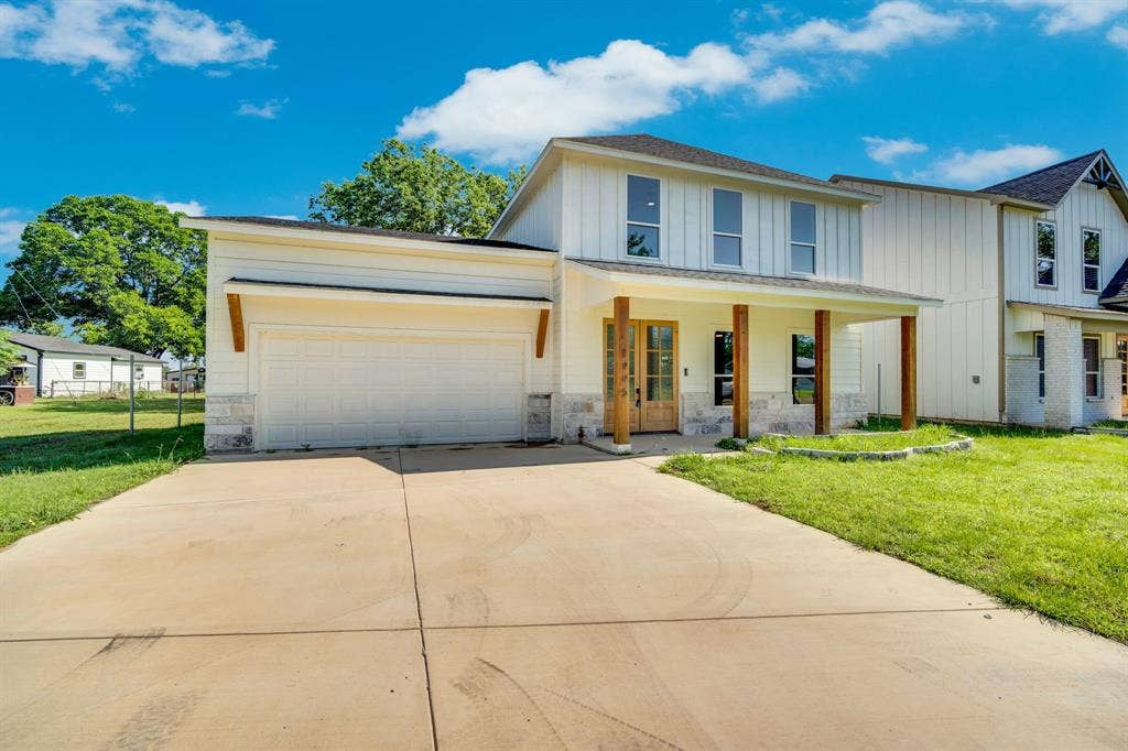 1995 Lakeview Drive, Kemp, TX 75143 Two-story exterior with board and batten siding, stone facade accents, covered front porch with wood columns, and a two-car garage