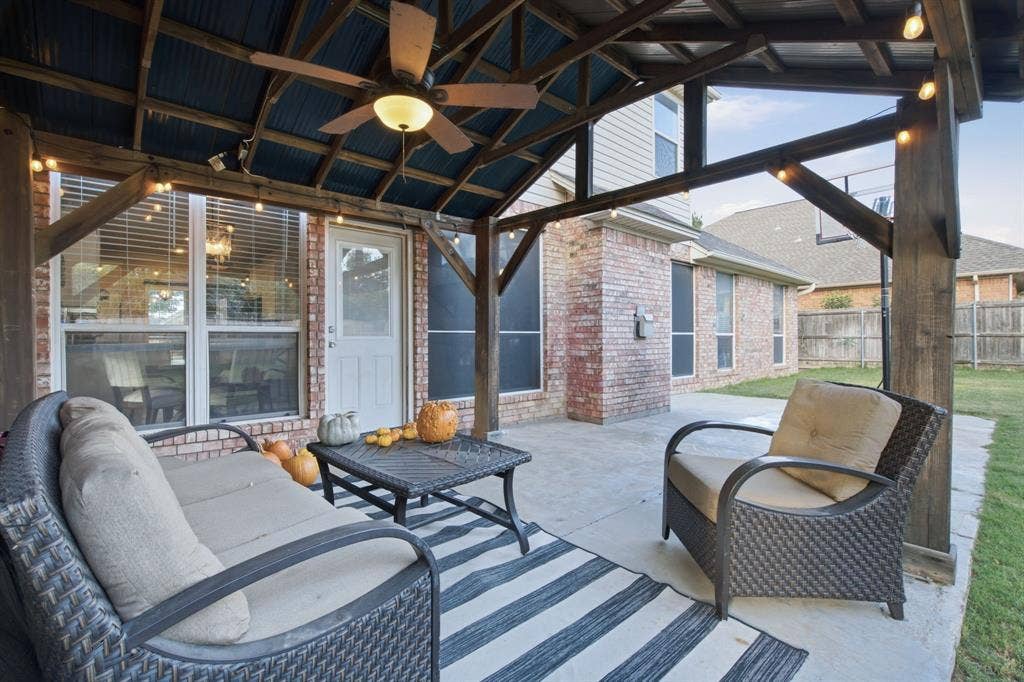 Covered patio featuring a timber-frame pergola, concrete flooring, and a ceiling-mounted fan with integrated lighting
