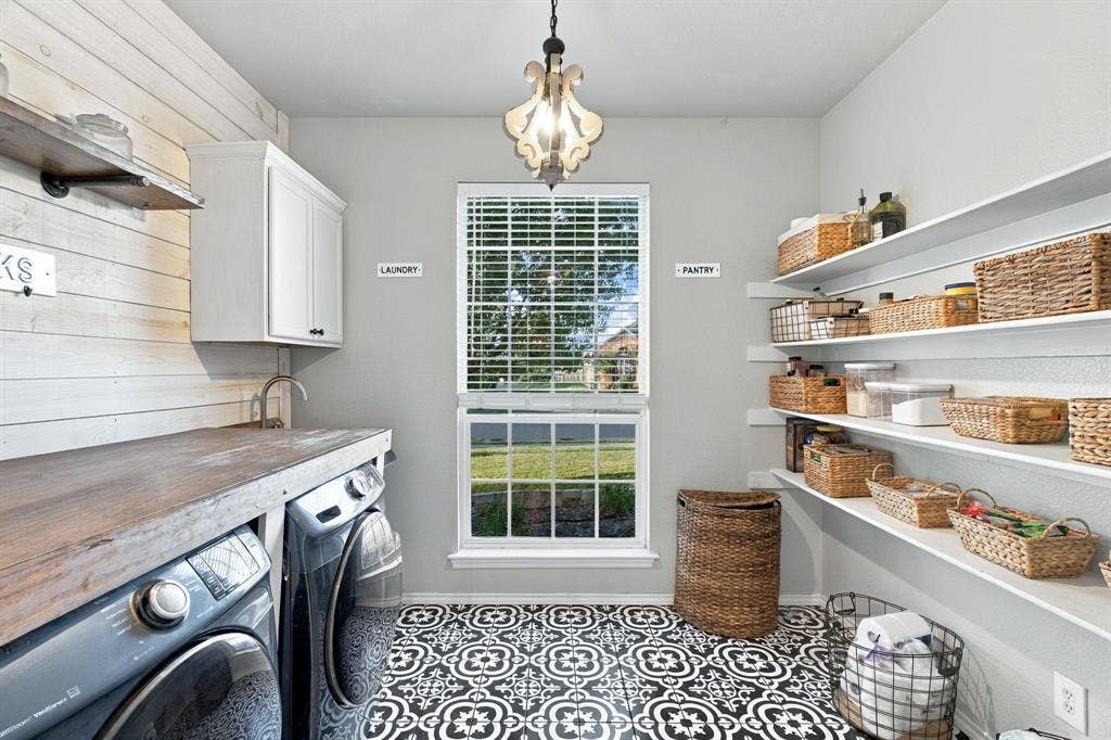 Utility room featuring decorative patterned floor tile, custom wall-mounted shelving, wood-finish countertop, plank-style wall detailing, and an overhead pendant light fixture