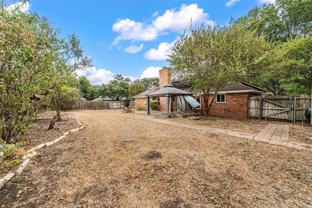 812 Regina Drive, Hewitt, TX 76643 Brick exterior with a prominent chimney, fenced backyard, and a covered patio structure