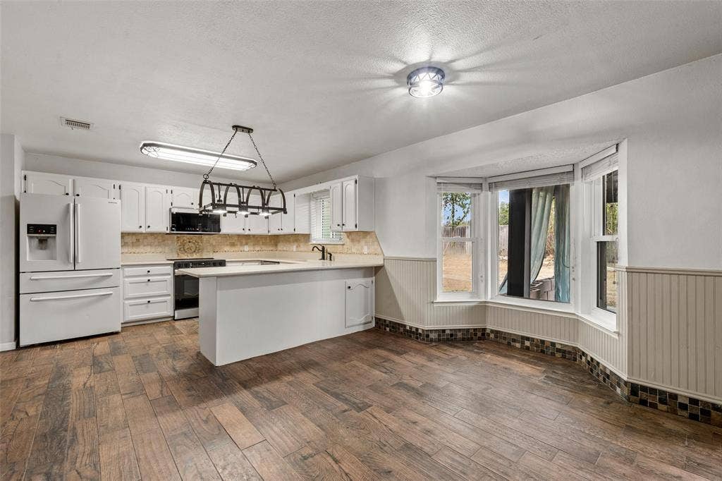 812 Regina Drive, Hewitt, TX 76643 Kitchen featuring wood-finish flooring, white cabinetry, a built-in oven, and a bay window