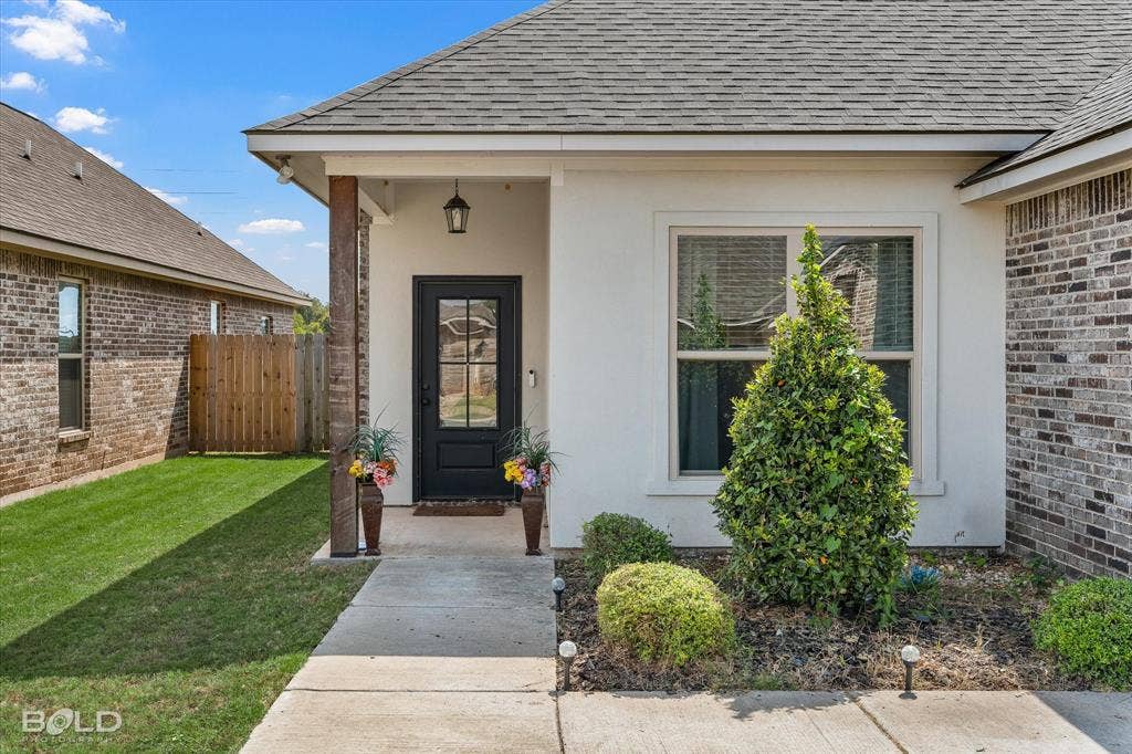 Brick and stucco exterior with a covered entry, a paneled front door with divided lites, and a gabled roof