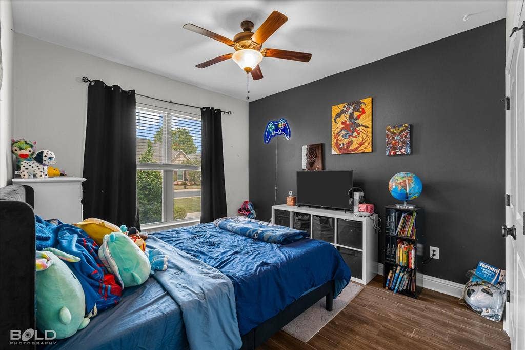 Wood-finish flooring, ceiling fan with integrated lighting, window with blinds, and white trim