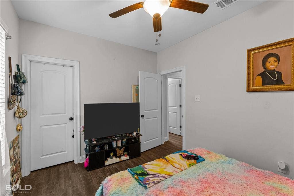Wood-finish flooring throughout, bright white walls, and a ceiling fan with integrated lighting
