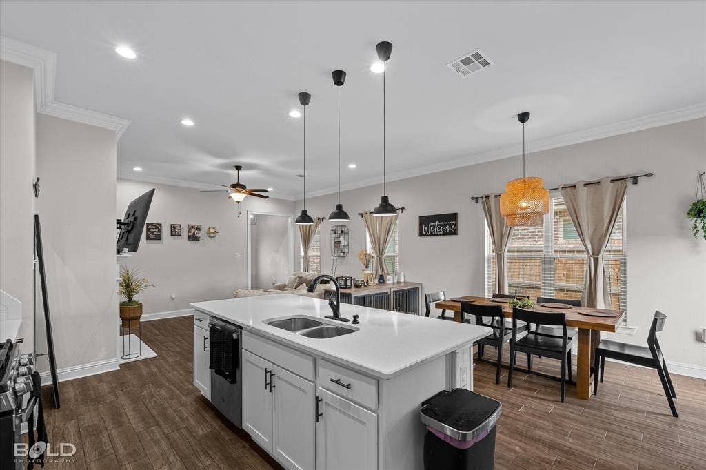 Open-concept living area with wood-finish flooring, recessed lighting, and crown molding