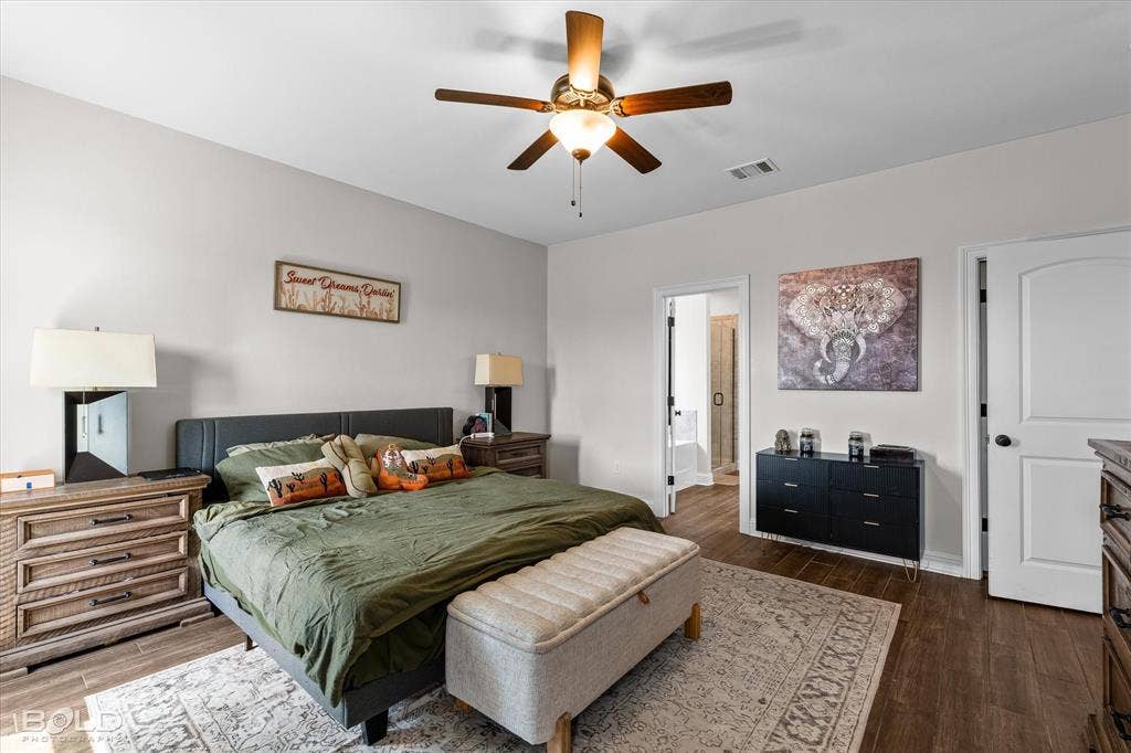 Wood-finish flooring, ceiling fan with integrated lighting, arched doorway, and a neutral color palette