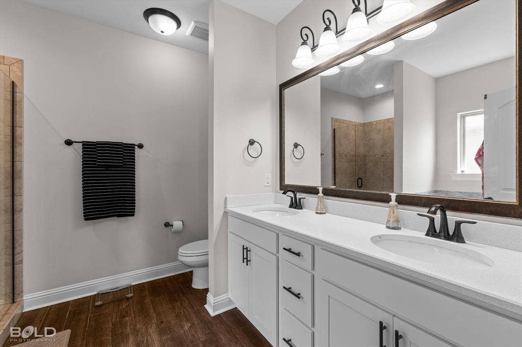 Dual vanity with white cabinetry and matte black hardware, white solid surface countertops, and matte black fixtures