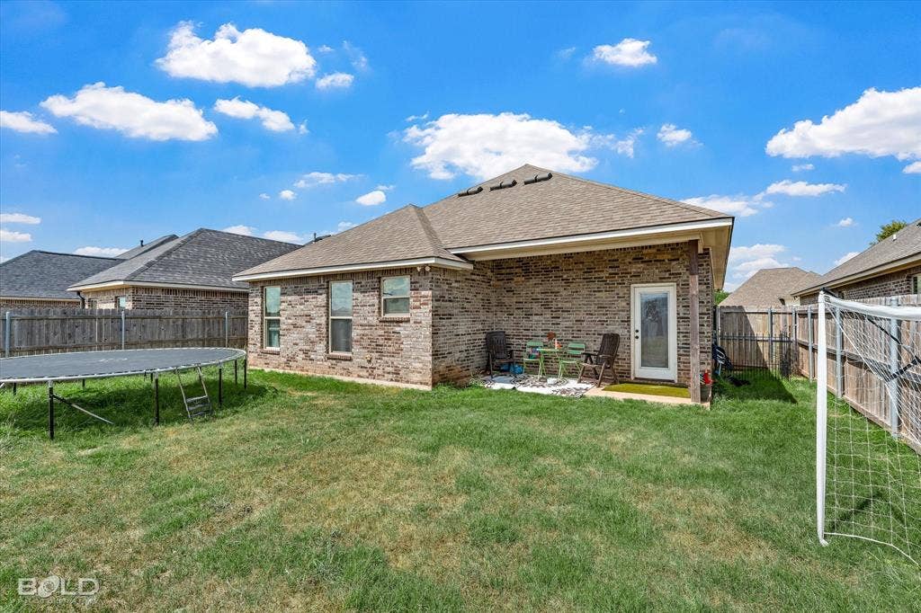 Brick exterior, shingle roof, privacy fencing, concrete patio, exterior door with window insert
