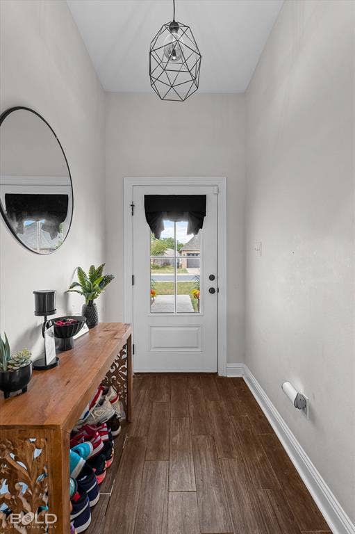 Entryway featuring wood-finish flooring, a white paneled door with glass inserts, and a geometric pendant light