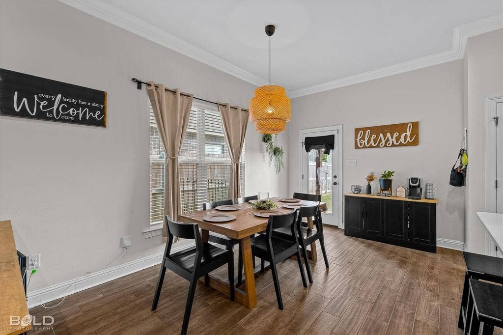 Wood-finish flooring with crown molding, a built-in buffet with a wood countertop, and a rear door with an integrated window