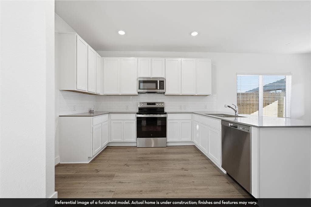 5218 Noland Drive, Princeton, TX 75071 Kitchen featuring white shaker-style cabinetry, stainless steel appliances, quartz countertops, subway tile backsplash, and wood-finish flooring