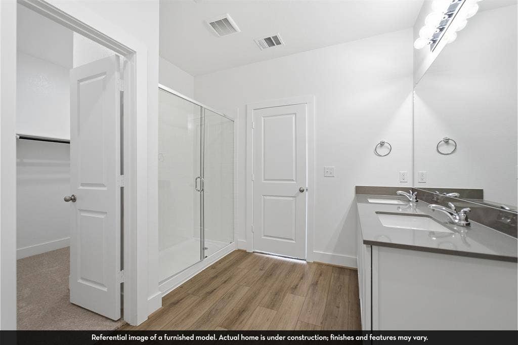 5218 Noland Drive, Princeton, TX 75071 Dual-sink vanity with solid-surface countertop, glass-enclosed shower, and wood-finish flooring