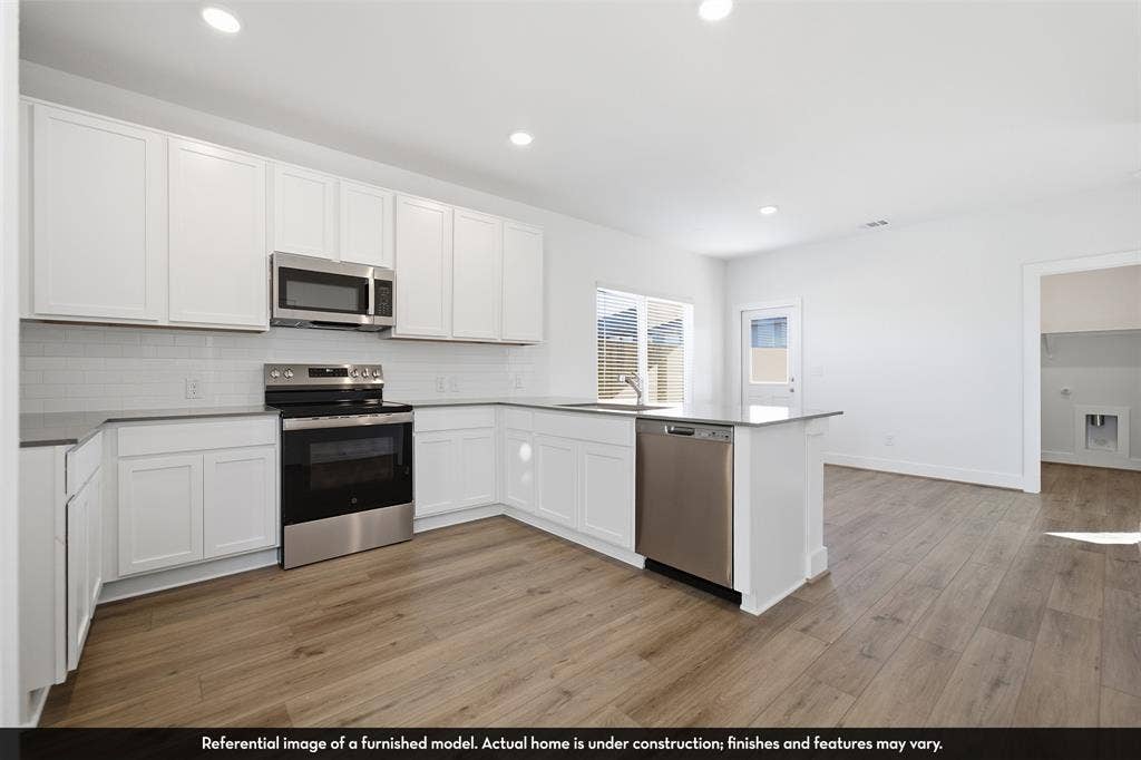5218 Noland Drive, Princeton, TX 75071 Kitchen featuring white Shaker-style cabinetry, stainless steel appliances, white subway tile backsplash, solid-surface countertops, and wood-finish flooring