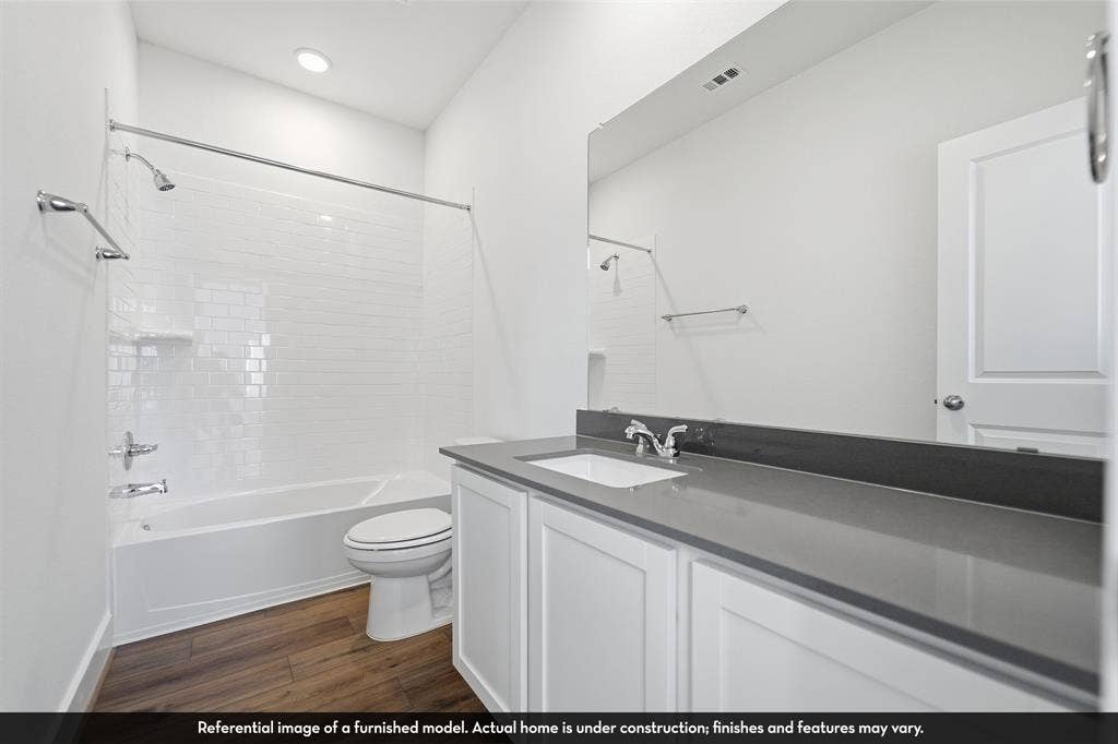 821 Whitmore Drive, Princeton, TX 75071 Bathroom featuring a white vanity with a dark gray countertop, an undermount rectangular sink, wood-finish flooring, and a tub-shower combination with white subway tile surround