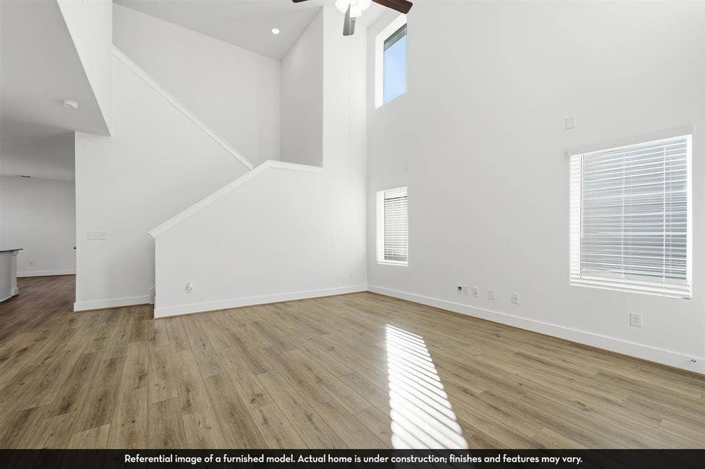 821 Whitmore Drive, Princeton, TX 75071 Open-concept interior featuring vaulted ceilings, wood-finish flooring, multi-level windows, and a ceiling fan with integrated light fixture