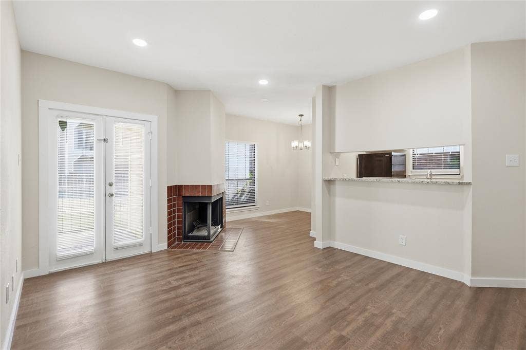4414 Point Boulevard, #115, Garland, TX 75043 Wood-finish flooring, recessed lighting, brick-clad fireplace, double French doors, and a built-in pass-through window with a granite-style countertop