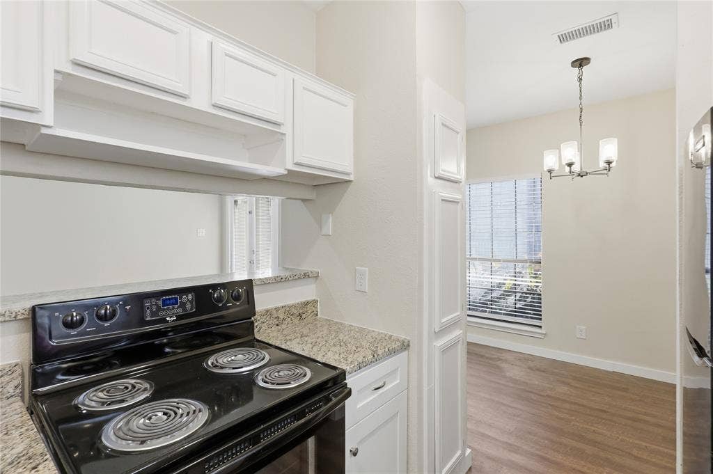 4414 Point Boulevard, #115, Garland, TX 75043 White cabinetry, granite-finish countertops, and wood-finish flooring