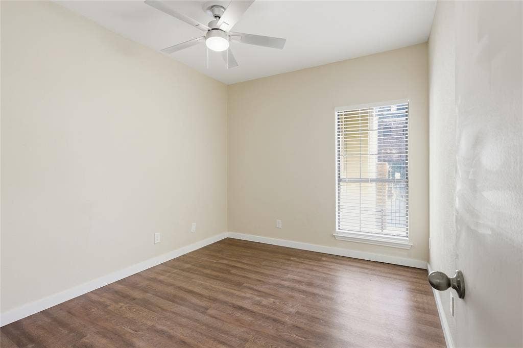 4414 Point Boulevard, #115, Garland, TX 75043 Wood-finish flooring with white baseboards, a ceiling fan with integrated lighting, and a window with blinds