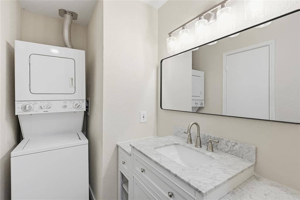 4414 Point Boulevard, #115, Garland, TX 75043 Laundry stackable unit, vanity with integrated sink, stone countertop, brushed nickel faucet, and a rectangular framed mirror