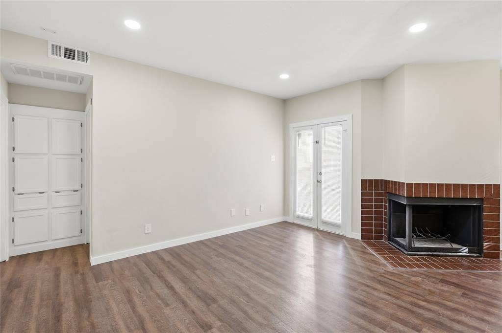 4414 Point Boulevard, #115, Garland, TX 75043 Wood-finish flooring, recessed lighting, built-in cabinetry, French doors, and a brick-surround fireplace