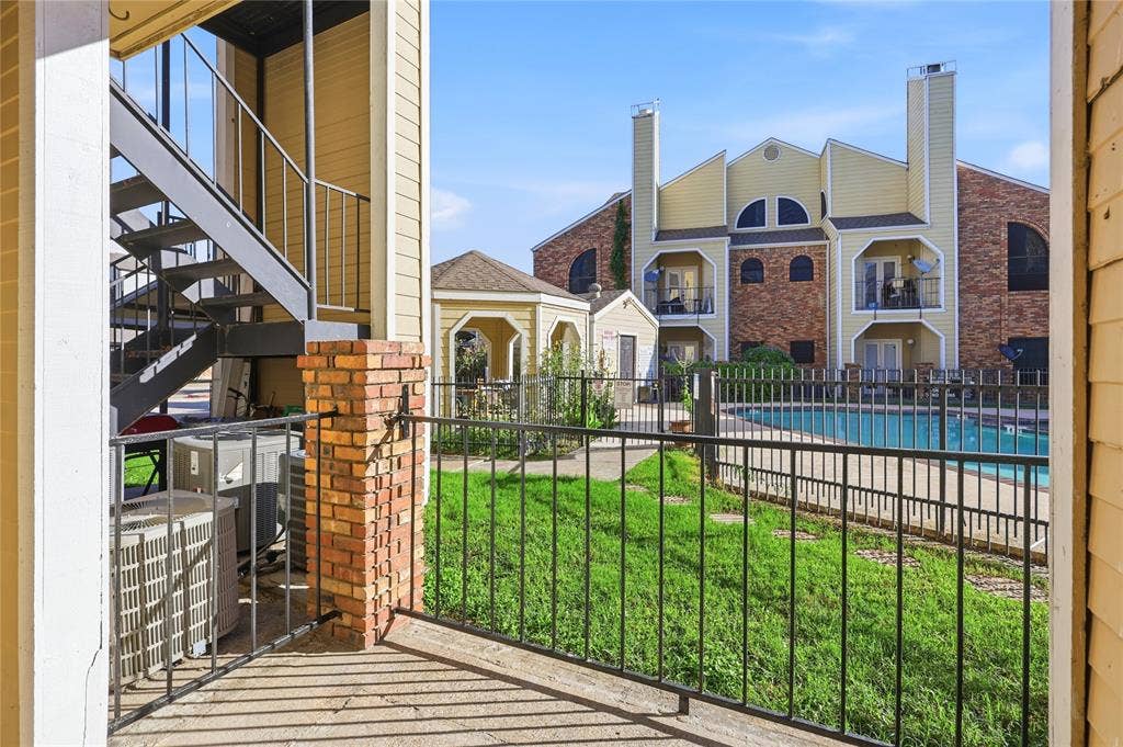 4414 Point Boulevard, #115, Garland, TX 75043 Patio with brick pillar accents and black metal railing overlooking a fenced swimming pool, central gazebo, and landscaped green space