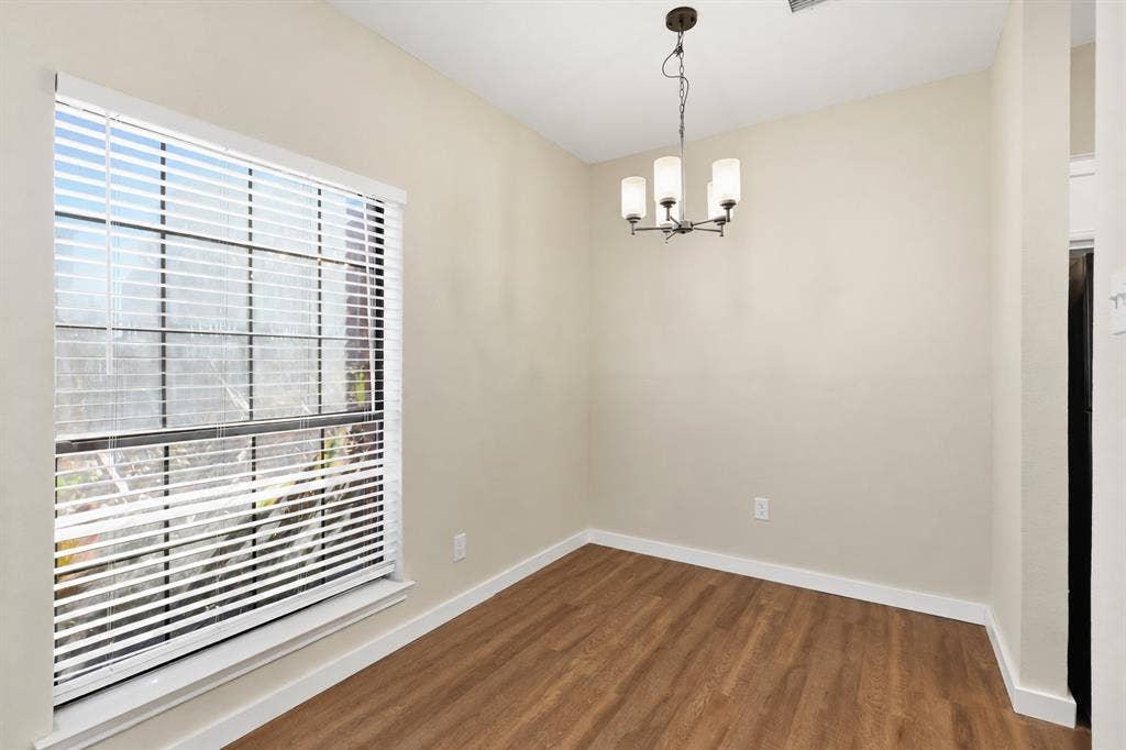 4414 Point Boulevard, #115, Garland, TX 75043 Natural light from a prominent window, wood-finish flooring, neutral wall tones, white trim, and a contemporary chandelier