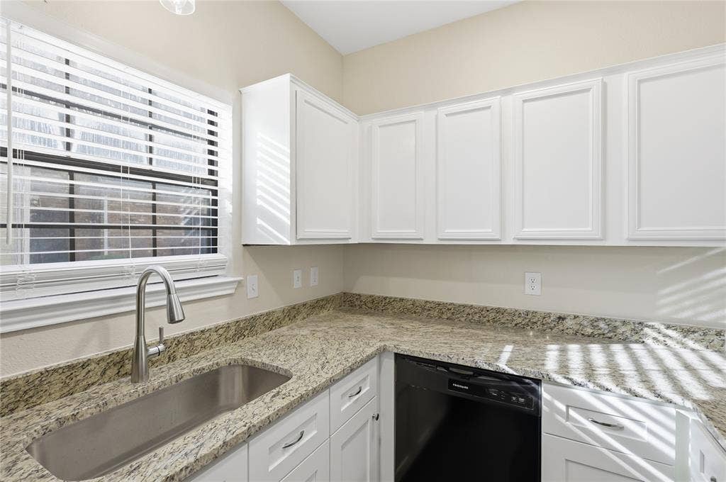 4414 Point Boulevard, #115, Garland, TX 75043 White shaker-style cabinetry, granite countertops, undermount stainless steel sink, gooseneck faucet, and a black dishwasher
