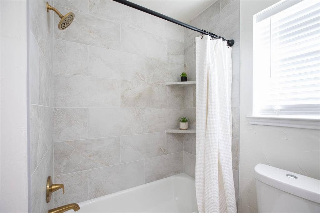 Newly tiled bathtub surround and gold faucets