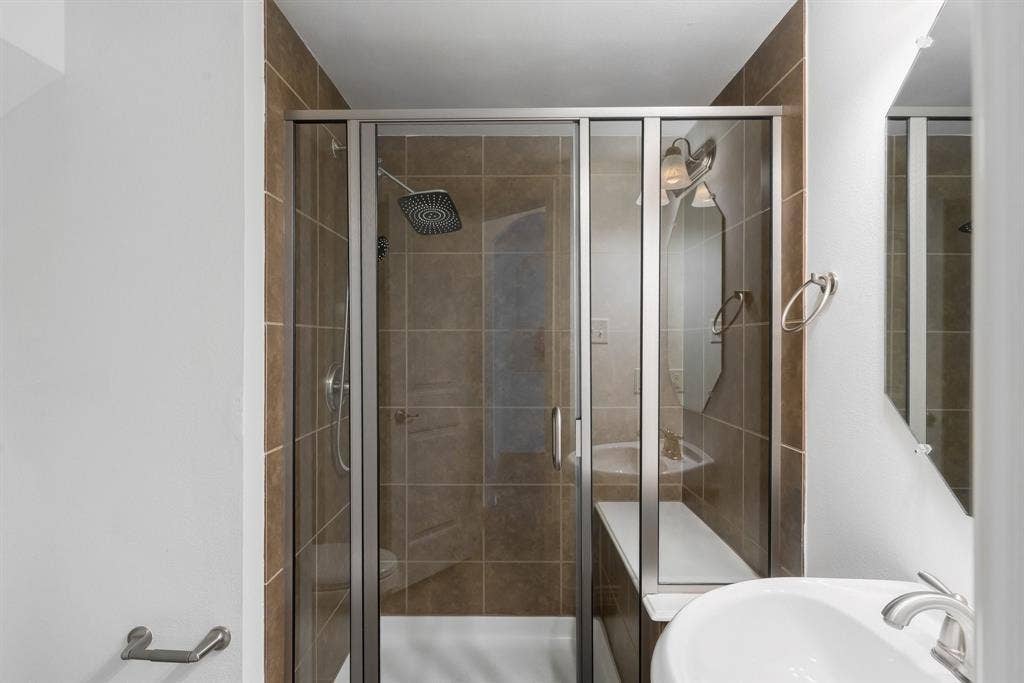 Glass-enclosed shower with brown tile surround and a built-in bench