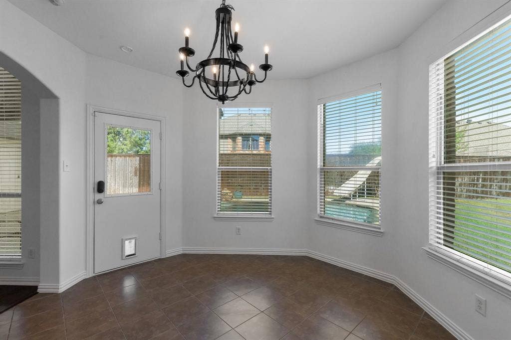 Tile flooring, multi-pane windows with blinds, arched entry, and a decorative chandelier