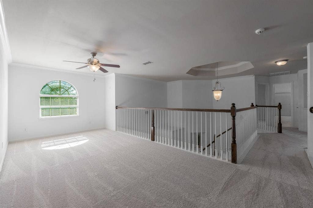Arched window with blinds, ceiling fan, carpeted flooring, decorative chandelier, and tray ceiling detail