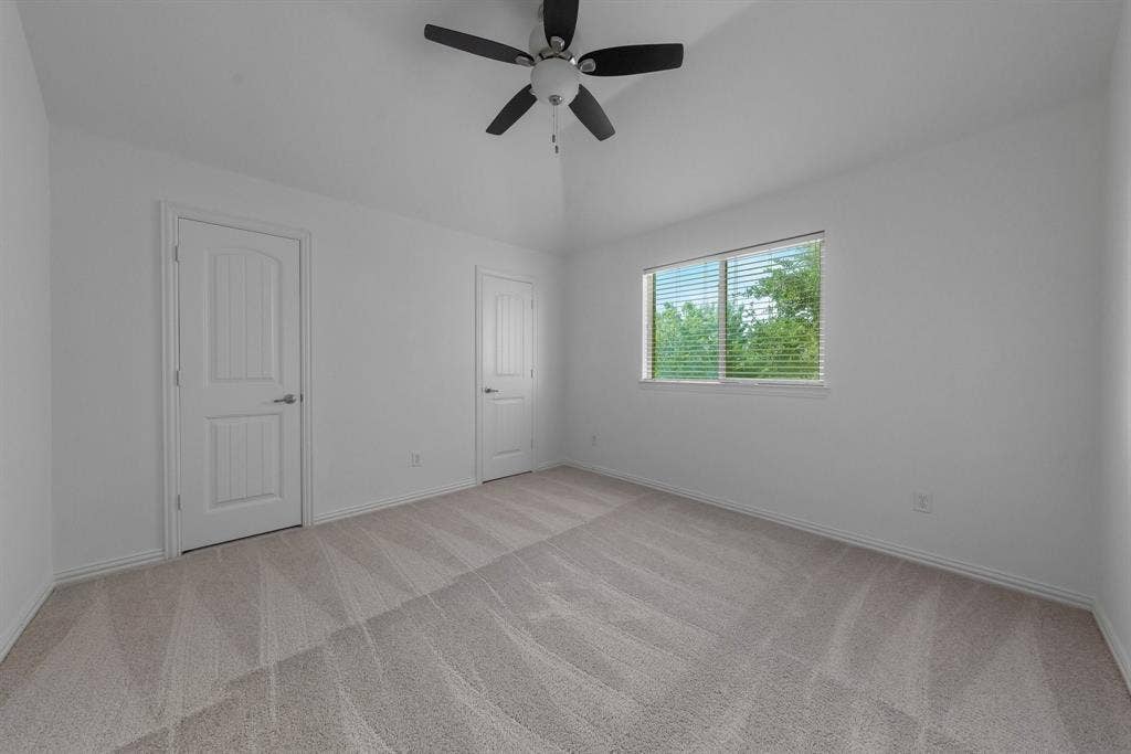 Vaulted ceiling with a ceiling fan, light gray carpet flooring, and a window with blinds