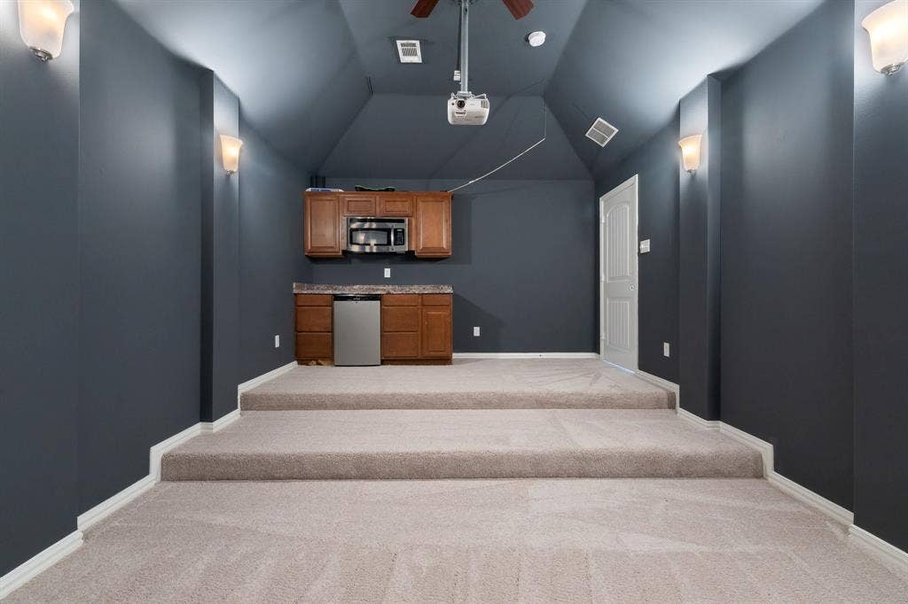 Tiered carpeting, recessed ceiling, built-in cabinetry, integrated microwave, and a beverage refrigerator