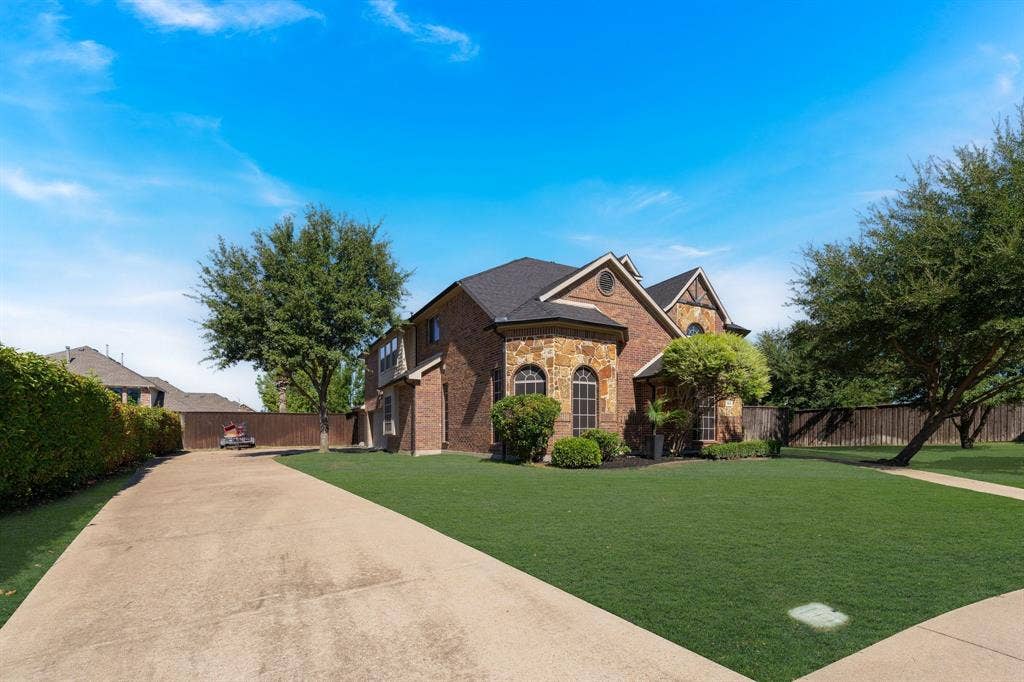 Brick and stone exterior with arched windows, gabled roofline, and an expansive lawn