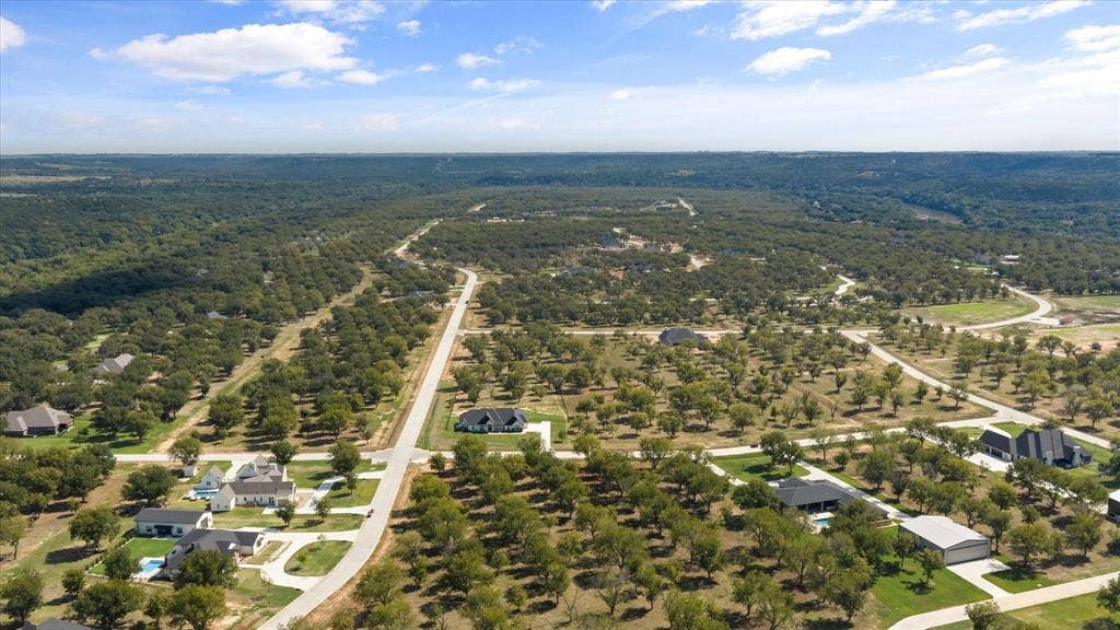 2013 Skylane Drive, Granbury, TX 76049 Aerial perspective of a master-planned community featuring paved roadways, individual residential lots, clusters of mature hardwood trees, and vast wooded acreage