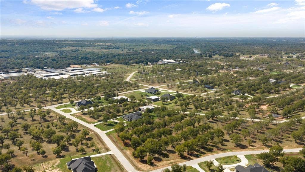 2013 Skylane Drive, Granbury, TX 76049 Aerial perspective of a rural residential area featuring expansive acreage, mature tree cover, paved road infrastructure, and natural landscape terrain
