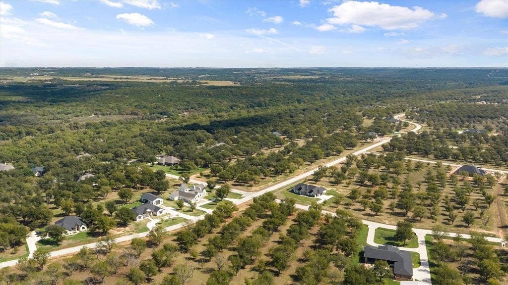 2013 Skylane Drive, Granbury, TX 76049 Aerial perspective of a rural residential landscape featuring expansive acreage, mature tree clusters, paved thoroughfares, and scattered single-story dwellings