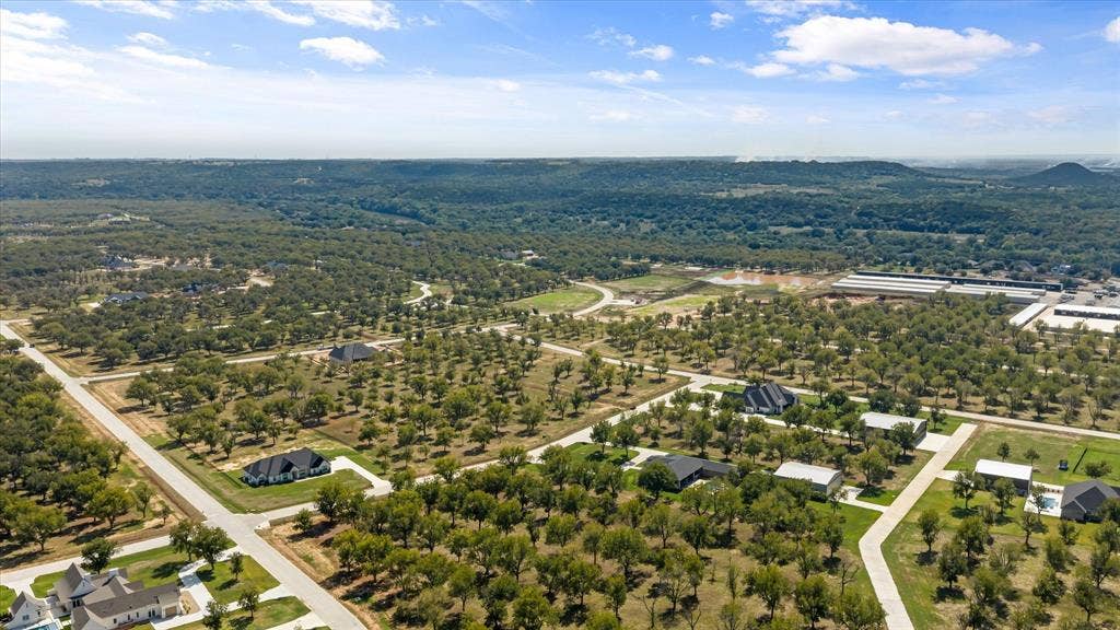 2013 Skylane Drive, Granbury, TX 76049 Aerial perspective featuring expansive acreage, mature tree clusters, paved streets, and a distant hilly horizon