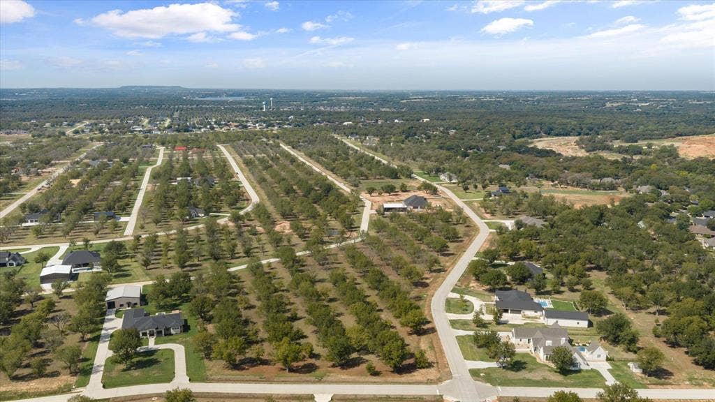 2013 Skylane Drive, Granbury, TX 76049 Aerial perspective of expansive residential acreage featuring mature trees, paved roadways, concrete driveways, and open land