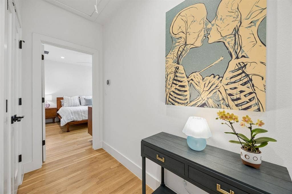 7207 Gaston Avenue, #903, Dallas, TX 75214 Hallway featuring light wood finished floors separating the primary and guest suite with vaulted ceiling. The spacious hallway provides easy access and a welcoming transition between the main living areas and the private suites.