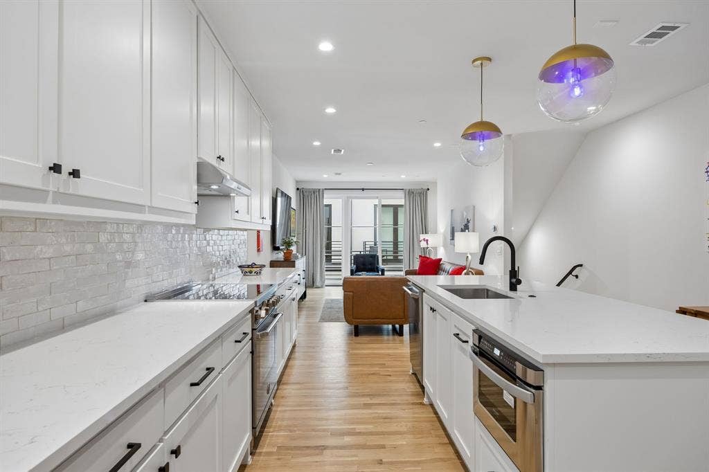 7207 Gaston Avenue, #903, Dallas, TX 75214 Chef inspired kitchen featuring high end Bertazzoni appliances, stainless steel finishes, light oak wood flooring, and crisp white shaker style cabinetry, all complemented by light stone countertops and a spacious island with built in sink.