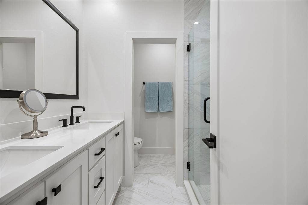 7207 Gaston Avenue, #903, Dallas, TX 75214 Bathroom with double vanity, a walk-in shower stall, and light stone finish flooring