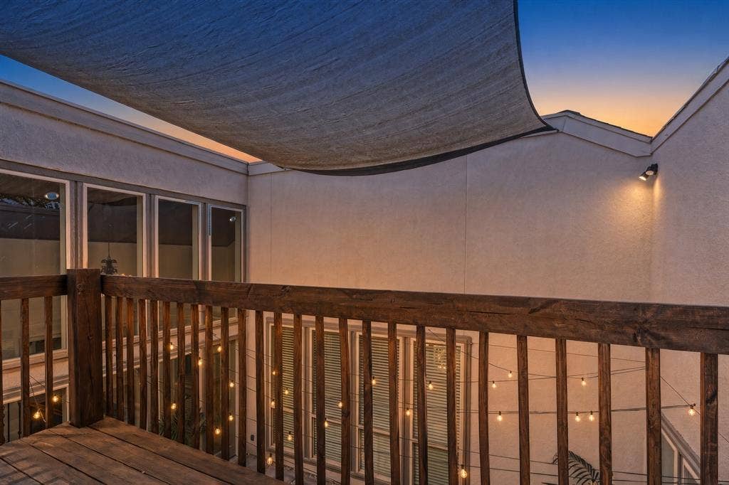 6423 Ridgemont Drive, Dallas, TX 75214 Evening on the Upper-level deck with wood railing overlook the Courtyard, protective shade covering, exterior wall lighting, and multiple windows