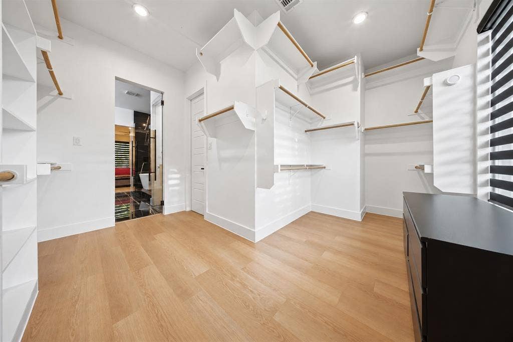 522 S Clark Road, Cedar Hill, TX 75104 Spacious closet with wood-finish flooring, built-in shelving, integrated hanging rods, recessed lighting, and a dark wood-finish cabinet